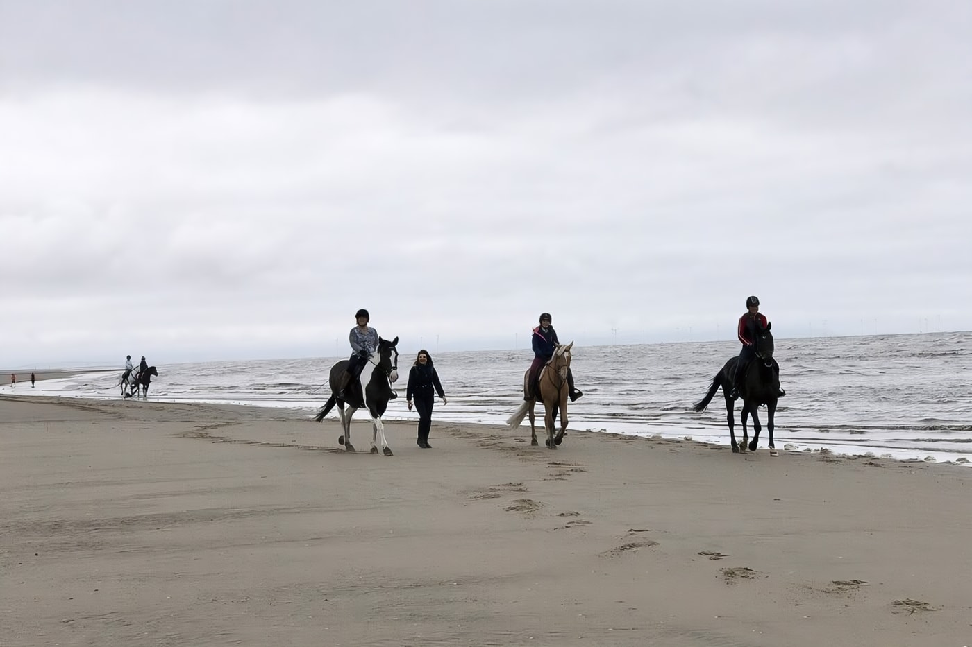 Des cavaliers sur une plage de sable, en Normandie