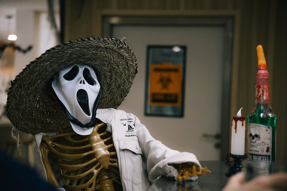 Squelette déguisé, bouteille à la main, décor d’Halloween